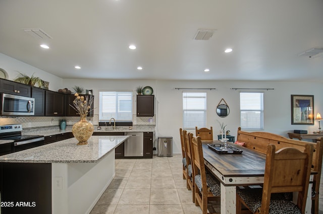 kitchen with tasteful backsplash, stainless steel appliances, a wealth of natural light, and light tile patterned flooring