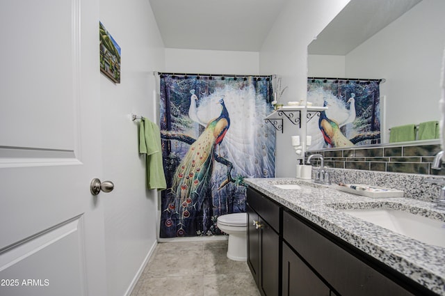 bathroom featuring double vanity, a sink, toilet, and baseboards