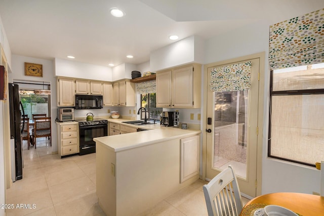 kitchen with black appliances, sink, light tile patterned floors, cream cabinetry, and kitchen peninsula