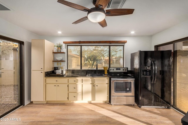 kitchen with cream cabinetry, black refrigerator with ice dispenser, stainless steel range with electric stovetop, and a healthy amount of sunlight