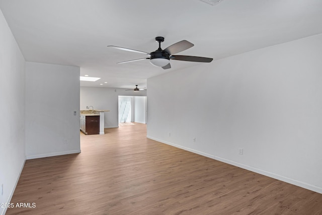 unfurnished living room with hardwood / wood-style flooring, sink, and ceiling fan