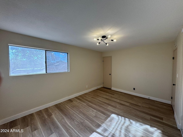 unfurnished bedroom featuring a textured ceiling, wood finished floors, and baseboards