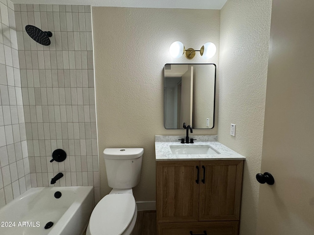 full bathroom featuring a textured wall, bathing tub / shower combination, toilet, and vanity