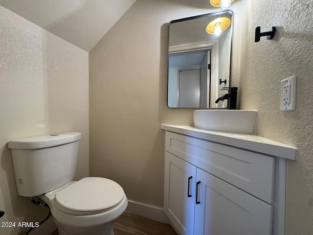 bathroom featuring a textured wall, toilet, wood finished floors, vanity, and baseboards