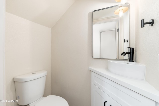 bathroom with vaulted ceiling, vanity, and toilet