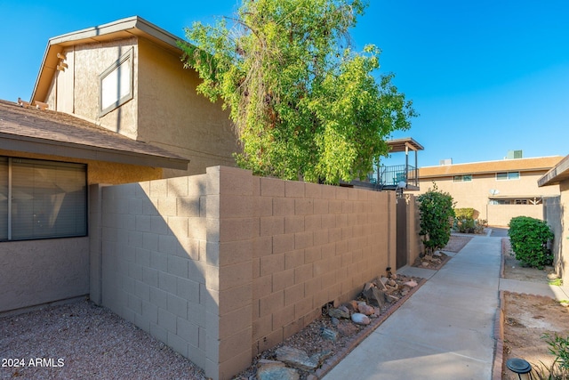 view of home's exterior with a shingled roof, fence, and stucco siding