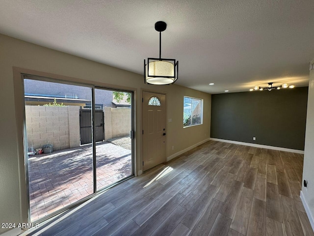 doorway with a textured ceiling, baseboards, and dark wood-type flooring