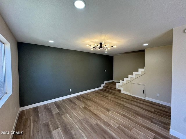 spare room with stairs, a textured ceiling, wood finished floors, and baseboards