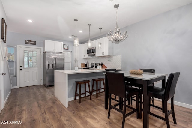 dining room featuring wood-type flooring, sink, and an inviting chandelier