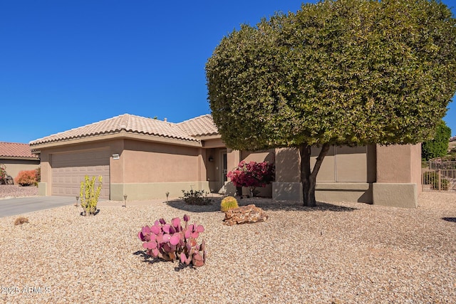 view of front facade with a garage, driveway, a tiled roof, and stucco siding