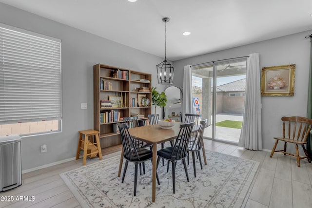 dining space featuring light wood-style flooring, a notable chandelier, and baseboards