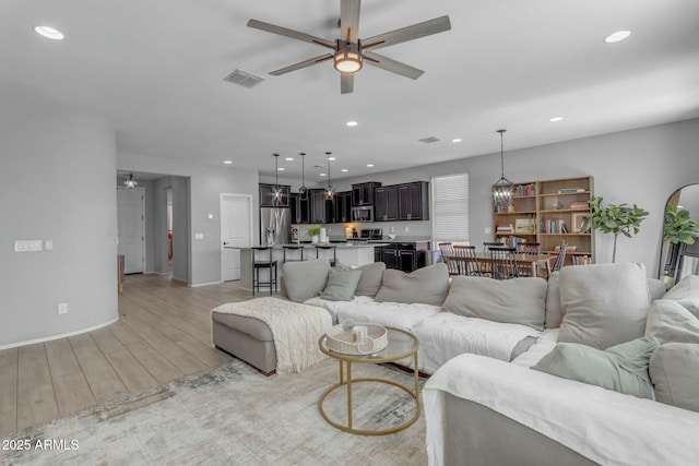 living area featuring a ceiling fan, visible vents, light wood finished floors, baseboards, and recessed lighting