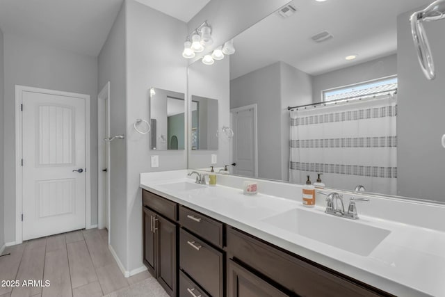 full bath featuring double vanity, visible vents, and a sink