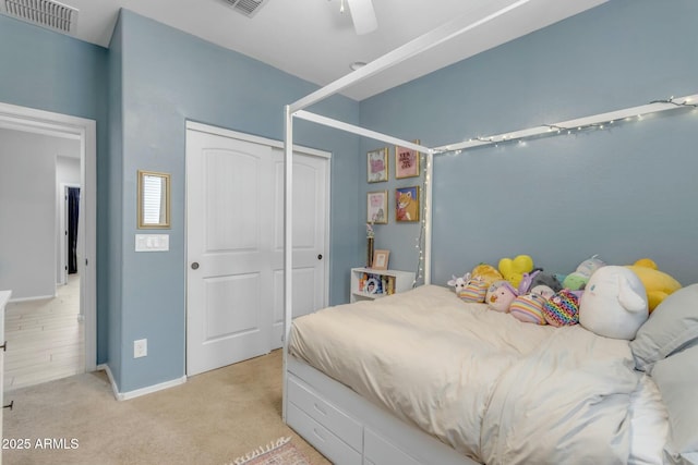 bedroom featuring visible vents, a closet, baseboards, light colored carpet, and ceiling fan