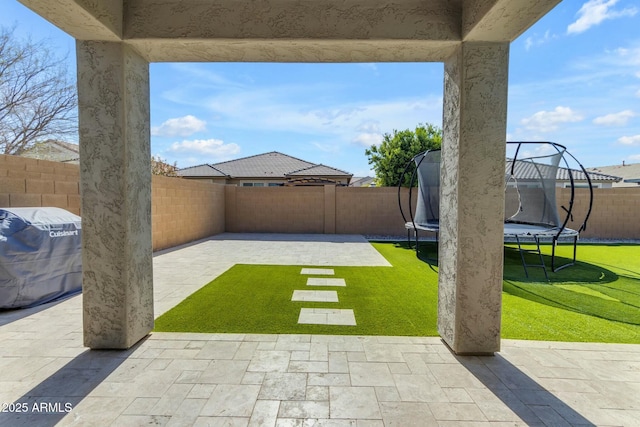 view of yard with a patio, a trampoline, and a fenced backyard