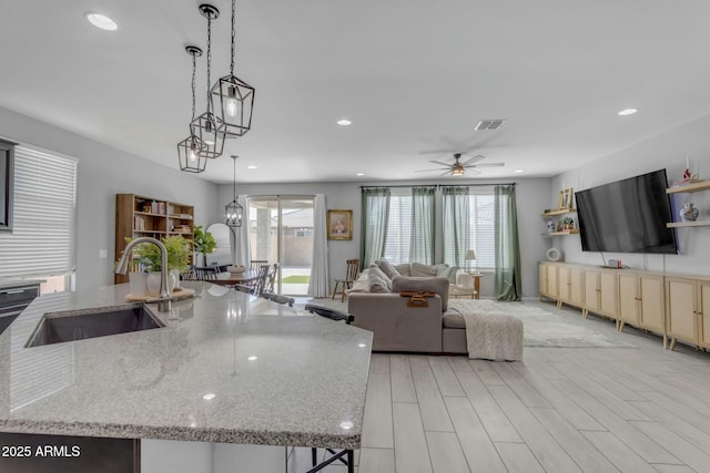 kitchen featuring a sink, open floor plan, recessed lighting, and hanging light fixtures