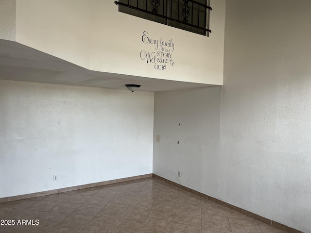 spare room with a towering ceiling and tile patterned floors