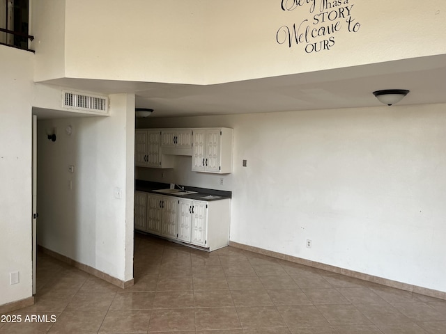 kitchen featuring sink, white cabinets, tile patterned floors, and a towering ceiling