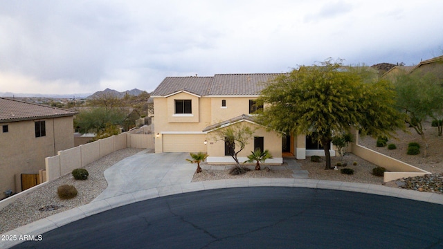 view of front of property featuring an attached garage, a tile roof, fence, concrete driveway, and stucco siding