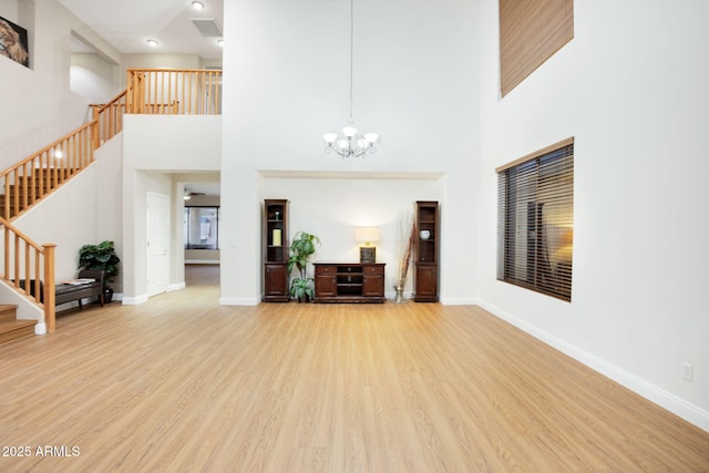 unfurnished living room with stairs, baseboards, and wood finished floors