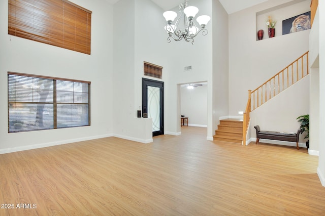 foyer entrance with stairway, an inviting chandelier, light wood-style flooring, and baseboards