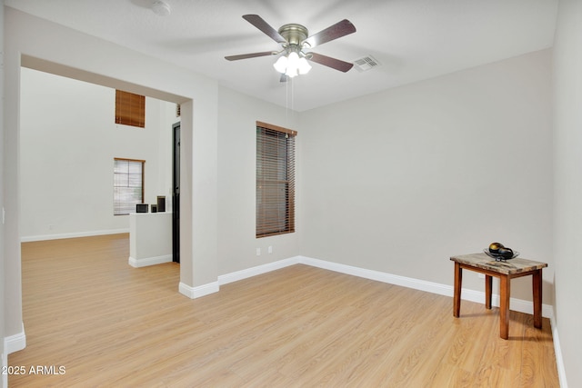 empty room with light wood-style floors, visible vents, baseboards, and a ceiling fan