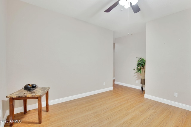 empty room with ceiling fan, light wood-style flooring, and baseboards