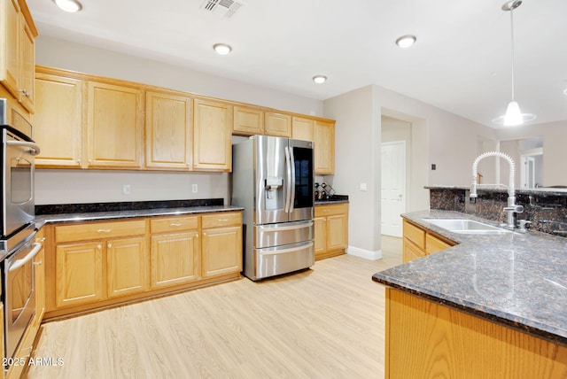 kitchen with visible vents, appliances with stainless steel finishes, light brown cabinets, a sink, and light wood-type flooring