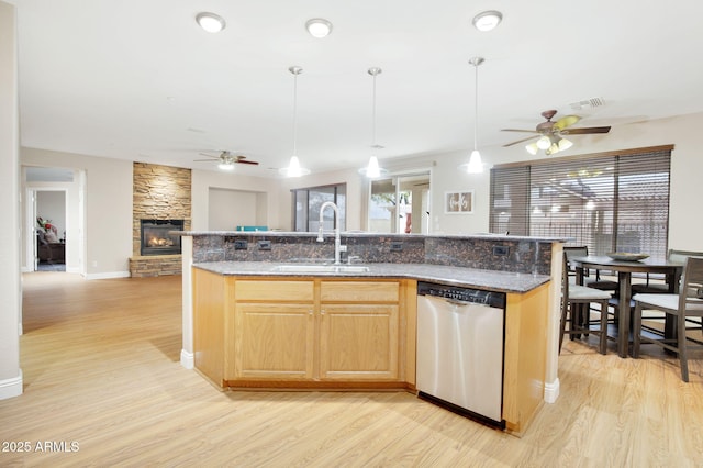 kitchen with a stone fireplace, a sink, visible vents, open floor plan, and stainless steel dishwasher