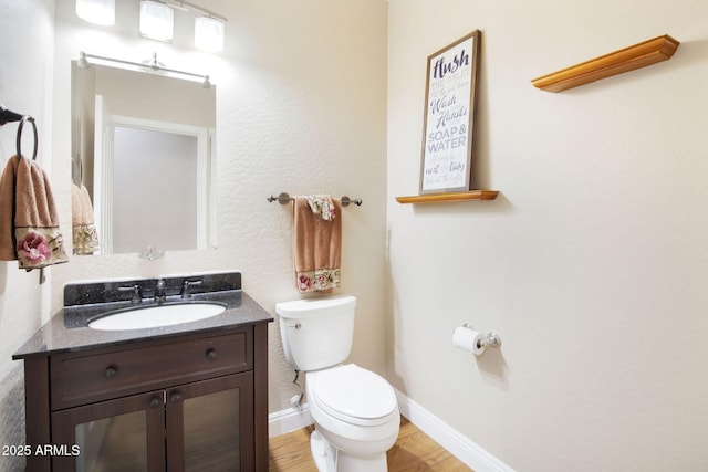 bathroom with toilet, baseboards, wood finished floors, and vanity