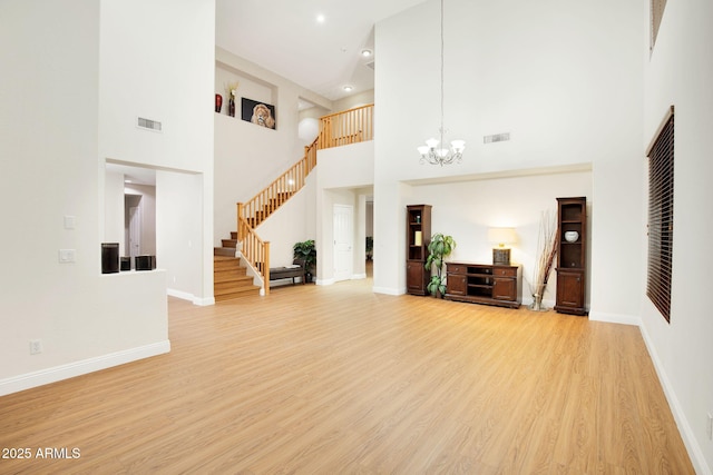 unfurnished living room with light wood finished floors, stairs, baseboards, and an inviting chandelier