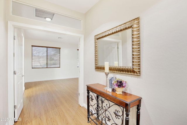 corridor featuring light wood finished floors, visible vents, and baseboards