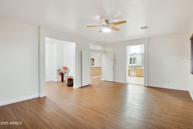 unfurnished living room featuring a ceiling fan, light wood-type flooring, visible vents, and baseboards