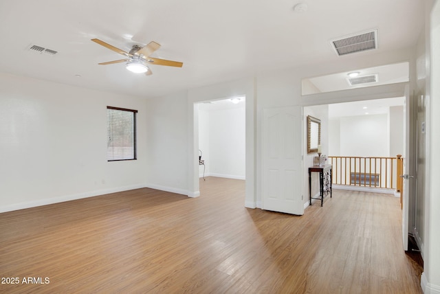 spare room with baseboards, visible vents, and wood finished floors