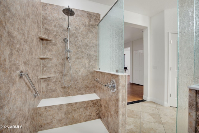 bathroom with baseboards, tiled shower, and tile patterned floors