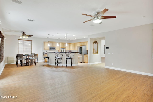 unfurnished living room featuring baseboards, a ceiling fan, visible vents, and light wood-style floors