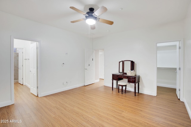 spare room featuring light wood finished floors, a ceiling fan, and baseboards