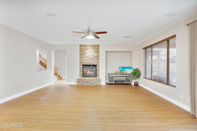 unfurnished living room featuring baseboards, visible vents, stairway, and light wood finished floors