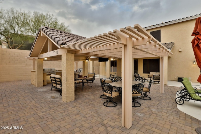 view of patio / terrace featuring grilling area, fence, outdoor dining area, exterior kitchen, and a pergola