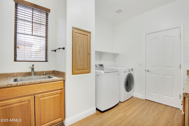 laundry room with visible vents, light wood-style flooring, a sink, washer and dryer, and baseboards