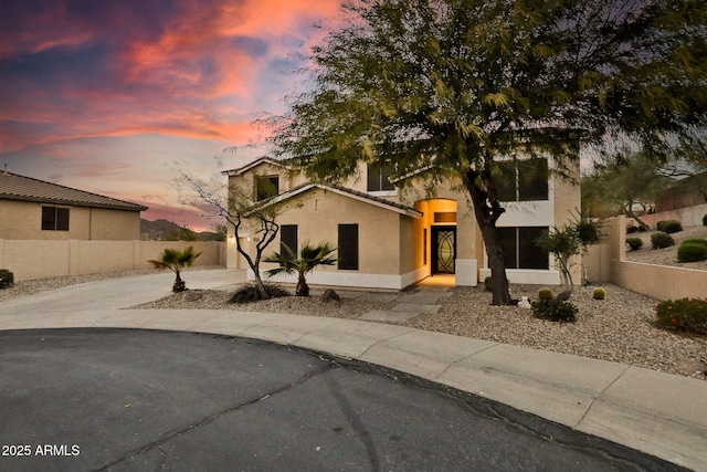 view of front of home featuring a garage, stucco siding, driveway, and fence