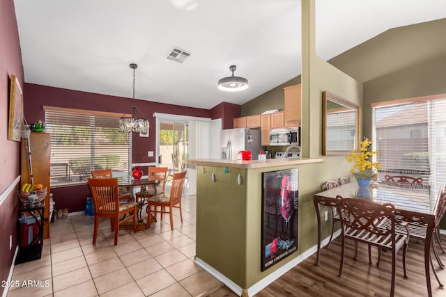 kitchen with visible vents, light brown cabinets, a chandelier, vaulted ceiling, and stainless steel appliances