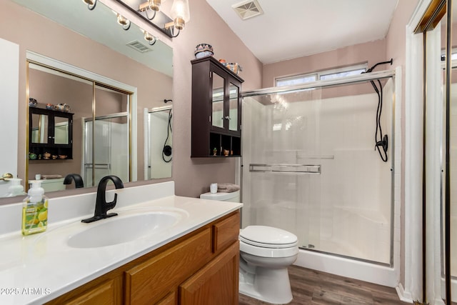 bathroom with toilet, visible vents, a shower stall, and wood finished floors