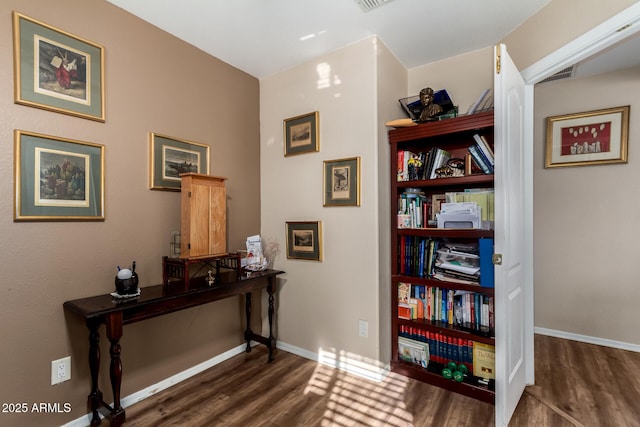 interior space with baseboards, wood finished floors, and visible vents