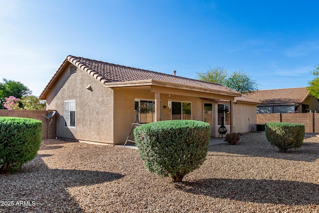 view of front of home with a tiled roof, fence, cooling unit, and stucco siding