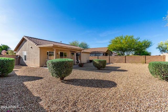 back of property with a tile roof, a fenced backyard, and stucco siding