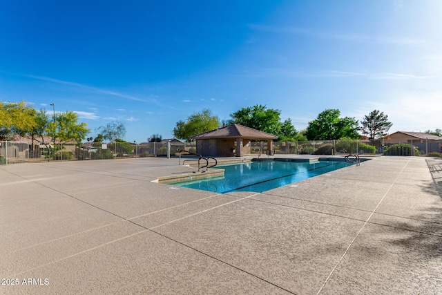 community pool with a gazebo, fence, and a patio area