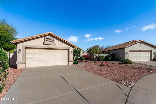 view of front of home with a tiled roof, a garage, stucco siding, and driveway