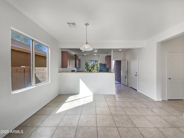 kitchen with visible vents, baseboards, a peninsula, freestanding refrigerator, and light tile patterned flooring