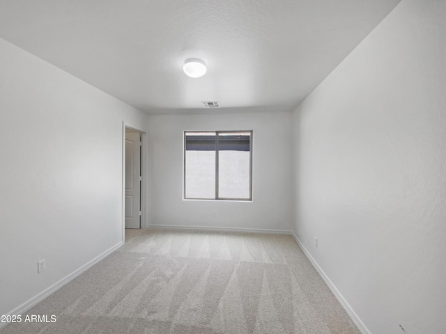 spare room with carpet flooring, baseboards, and visible vents